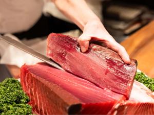 a person cutting a piece of meat with a knife at Hotel Abest Sapporo in Sapporo