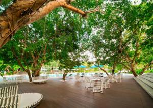 a patio with white chairs and tables and trees at Condotel in Tambuli Seaside Studio - F21K in Maribago