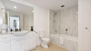 a white bathroom with a sink and a toilet and a tub at Stylish Apartment in Melbourne