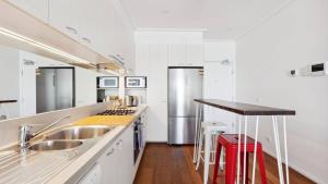a white kitchen with a sink and a counter at Stylish Apartment in Melbourne