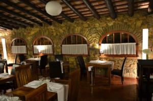 a restaurant with tables and chairs and a stone wall at Hotel Galena Mas Comangau in Begur