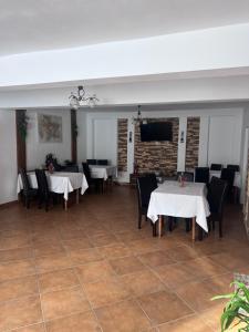 a dining room with tables and chairs and a flat screen tv at Casa Rares in Moieciu de Sus