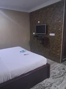 a bedroom with a bed and a tv on a brick wall at Coromandel Suites in Chennai