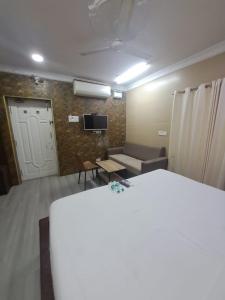a room with a bed and a couch and a tv at Coromandel Suites in Chennai