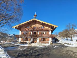 a large wooden house in the snow with a roof at Winklern Appartment Wildschütz in Kitzbühel