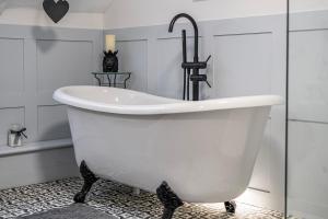 a white bath tub with a faucet in a bathroom at Old Rectory Cottage, Tostock in Tostock +15 photos