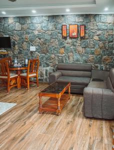 a living room with a couch and a table and a stone wall at Vaga Copper Castle in Vagamon