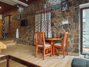 a table and chairs in a room with a stone wall at Vaga Copper Castle in Vagamon +37 photos