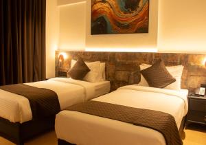 a hotel room with two beds and a painting on the wall at Magnus Lxia Premier, Kalyani Nagar Pune in Pune