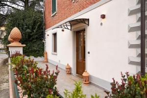 a white house with a brown door and some plants at Casa Vicky in Città di Castello