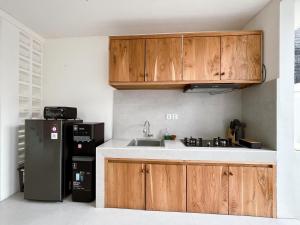 a kitchen with wooden cabinets and a black refrigerator at Ramady Guest House in Tumbak Bayuh