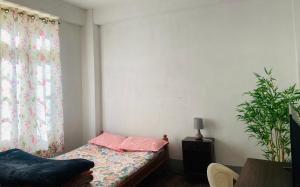 a bedroom with a bed with pink pillows and a plant at Maple Homestay in Kohīma
