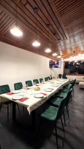 a long table in a room with green chairs at Pensiunea SOLEA in Ucea de Jos