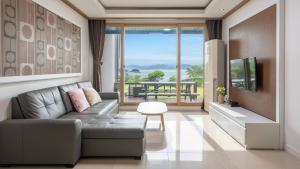 a living room with a couch and a tv at Yeosu falling in blue ocean view pension in Yeosu