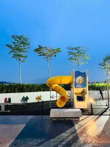 a yellow slide in a park with trees in the background at JC COZYsTAY RAWANG in Rawang