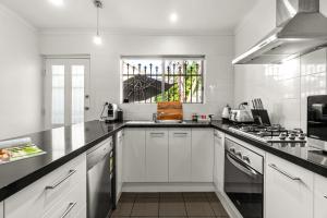 a white kitchen with a sink and a stove at The Arches-Beautiful 3-Bedroom Family Stay Near Adelaide Oval, City Events and Amazing Dining in North Adelaide