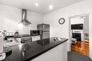 a kitchen with a black counter top and a clock at The Arches-Beautiful 3-Bedroom Family Stay Near Adelaide Oval, City Events and Amazing Dining in North Adelaide