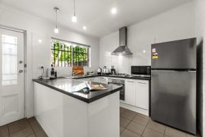 a kitchen with a stainless steel refrigerator and white cabinets at The Arches-Beautiful 3-Bedroom Family Stay Near Adelaide Oval, City Events and Amazing Dining in North Adelaide