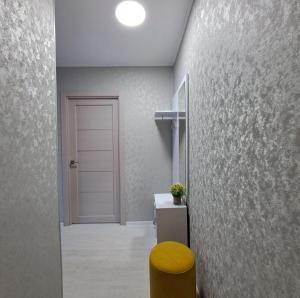 a hallway with a door and a yellow stool at Aizhan Bekshenova in Lenīnogorsk