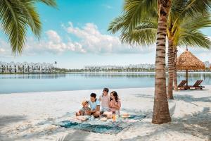 a family sitting on the beach under a palm tree at M2 Homestay vinhomes ocean in Gia Lâm Pho