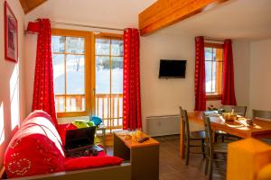 a living room with red curtains and a table at Goélia Les Chalets de Belledonne in Saint-Colomban-des-Villards +24 photos