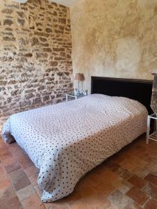 a bedroom with a large bed in a stone wall at Mine d'Ore Petit Gîte de la Chouette d'Or in Thoste