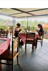 two women sitting at a table in a restaurant looking at their cell phones at Ryan Residence & Restaurant in Negombo