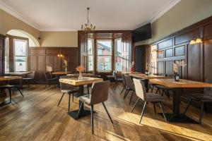 a restaurant with wooden tables and chairs and windows at Hillside Dunbar in Dunbar