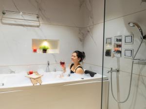 a woman sitting in a bath tub with a glass at Moustache Select Mcleodganj in Dharamshala