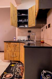 a kitchen with wooden cabinets and a black counter top at EKay's Space Najjera1 in Namugongo +2 photos