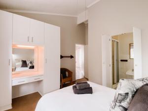 a white bedroom with a bed and a mirror at Treetops, Amblewood Guesthouse in Kenton on Sea