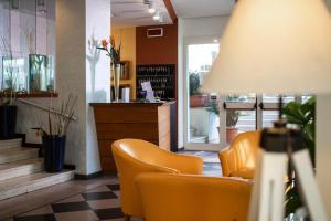 a waiting room with orange chairs in a store at Amadei Hotel Figaro & Apartments in Pesaro +71 photos