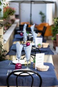 a row of tables with blue table cloth and glasses at Amadei Hotel Figaro & Apartments in Pesaro