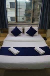 a bed with blue and white pillows and a window at Hotel krishnasai in Pune