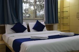 two beds with blue and white pillows in a bedroom at Hotel krishnasai in Pune