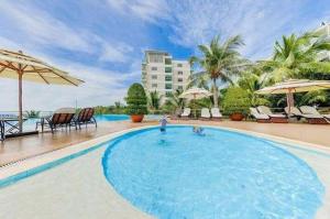 a large swimming pool with chairs and umbrellas at Căn Hộ OceanVista & Biệt Thự Sealink Phan Thiết - Mũi Né in Phan Thiet