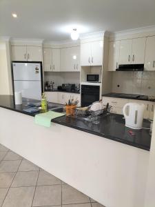 a kitchen with white cabinets and a black counter top at Maisie Haven in Brisbane