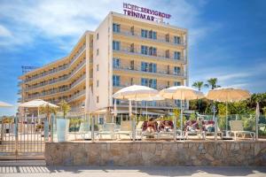 a hotel with chairs and umbrellas in front of a building at Hotel Servigroup Trinimar in Benicàssim