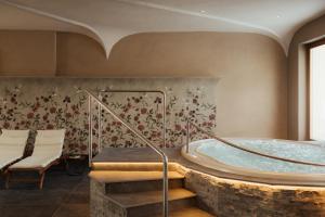 ein Whirlpool in einem Zimmer mit Steinboden in der Unterkunft Laguscei Dolomites Mountain Hotel in Arabba + 30 Fotos