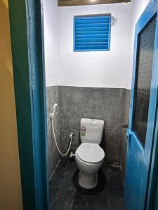 a bathroom with a toilet with a blue window at Hostel by Sri villa polwatta in Weligama