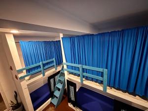 a bedroom with two bunk beds and blue curtains at Hostel by Sri villa polwatta in Weligama