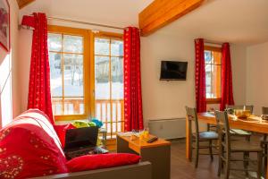 a living room with red curtains and a table with a laptop at Goélia Les Chalets de Belledonne in Saint-Colomban-des-Villards