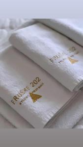 a pile of white towels with gold writing on them at Fruške 202 studio apartman in Vrdnik
