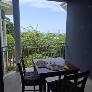 a table and chairs on a balcony with a view at Harmony Self-Catering Apartments in Beau Vallon