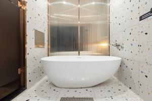 a bathroom with a large white tub on a tile floor at H-Avenue Hotel Yeongildae in Pohang +108 photos
