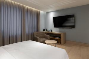 a hotel room with a bed and a chair and a television at H-Avenue Hotel Yeongildae in Pohang
