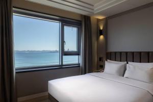 a bedroom with a large bed and a large window at H-Avenue Hotel Yeongildae in Pohang