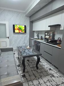 a kitchen with a table and a tv on the wall at Guest house 2 in Fergana