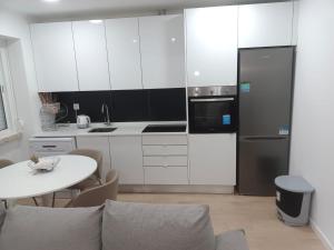 a white kitchen with a table and a refrigerator at Apartamento Cassoma in Amadora