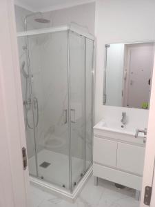 a bathroom with a glass shower and a sink at Apartamento Cassoma in Amadora